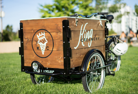 An Icicle Tricycles cedar box ice cream bike / trike in a grassy field on a sunny day branded for King Creamery