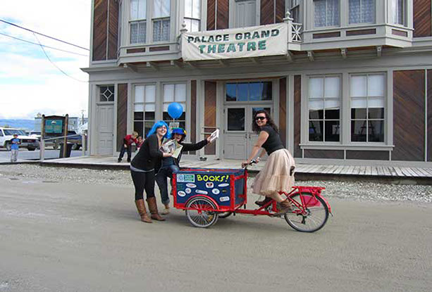 A peddling librarian on an Icicle Tricycles Book Bikes - bikes for book distribution, marketing, and delivery.