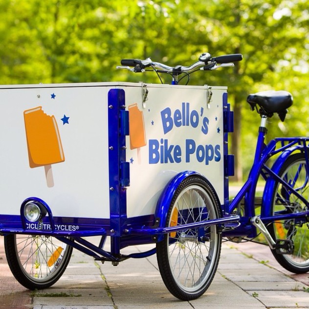 An icicle Tricycles ice cream bike / trike branded for Bello's bike Pops sitting in a park. 