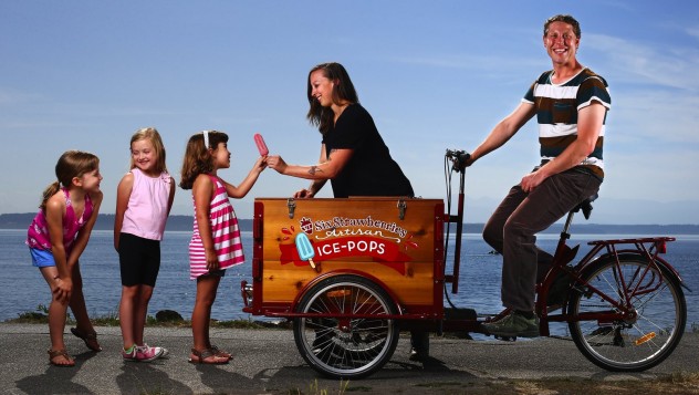 Vanessa Resler and her husband, Will Lemke, own Six Strawberries, a maker of artisan ice-pops. Pictured is one of their bicycle-powered coolers. Photographed at Golden Gardens in Seattle. At left are children of their friends. From left are, Isabella Pearson, 8, Kali Bowmer-Vath, 6, and Emmilia Pearson, 6 (all CQ). PACIFIC NORTHWEST MAGAZINE- TASTE COLUMN - SIX STRAWBERRIES ARTISAN ICE POPS - 147691 - 061115