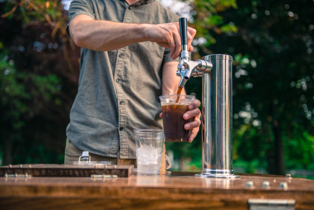 Person pouring cold brew coffee from a tap on a coffee bike cart