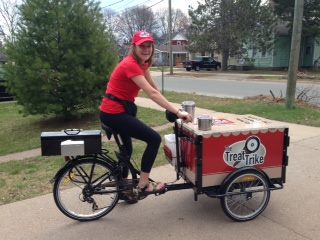 A woman riding Icicle Tricycles Ice Cream Bike / Trike branded for Treat Trike down the side walk