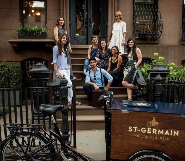 smiling people sitting behind a St-Germain Branded Wood Cargo Ice cream Bike Mobile Icicle Tricycles Designed Beverage Cart