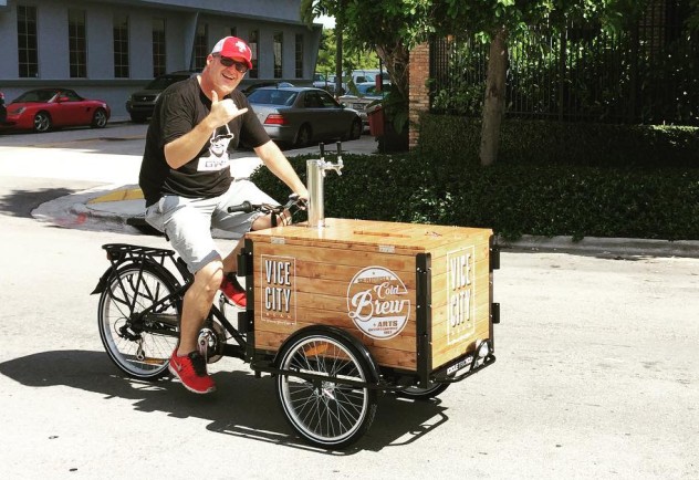 A man waving a shocka while riding a cold brew coffee bike cart