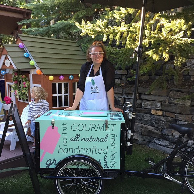 A custom branded gourmet ice cream vending bike parked next to a tiny home