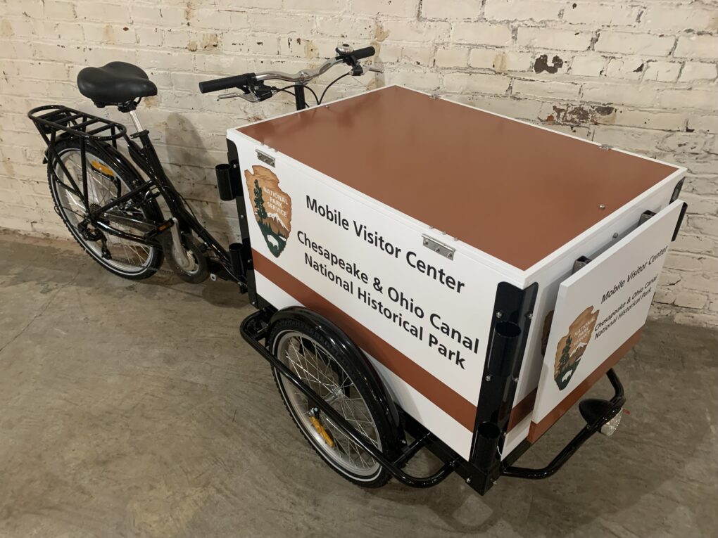 A Mobile Visitor Center Bike for the Chesapeake & Ohio Canal National Historical Park in front of a white brick wall.