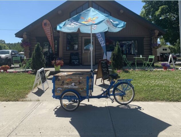 A Mobile Visitor Center Bike with an open umbrella is parked in front of the Bellingham, Washington visitor center during the day.
